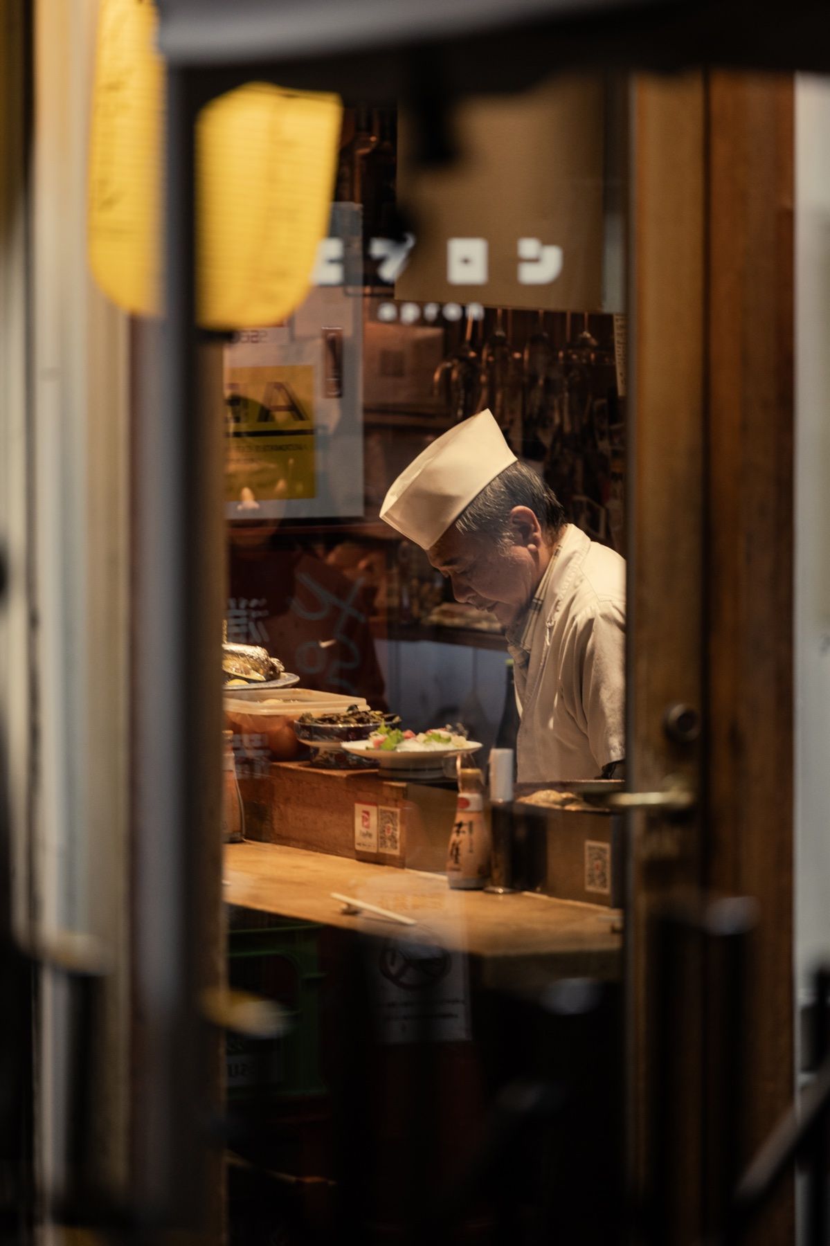 A chef at the counter, seen through a lit doorway