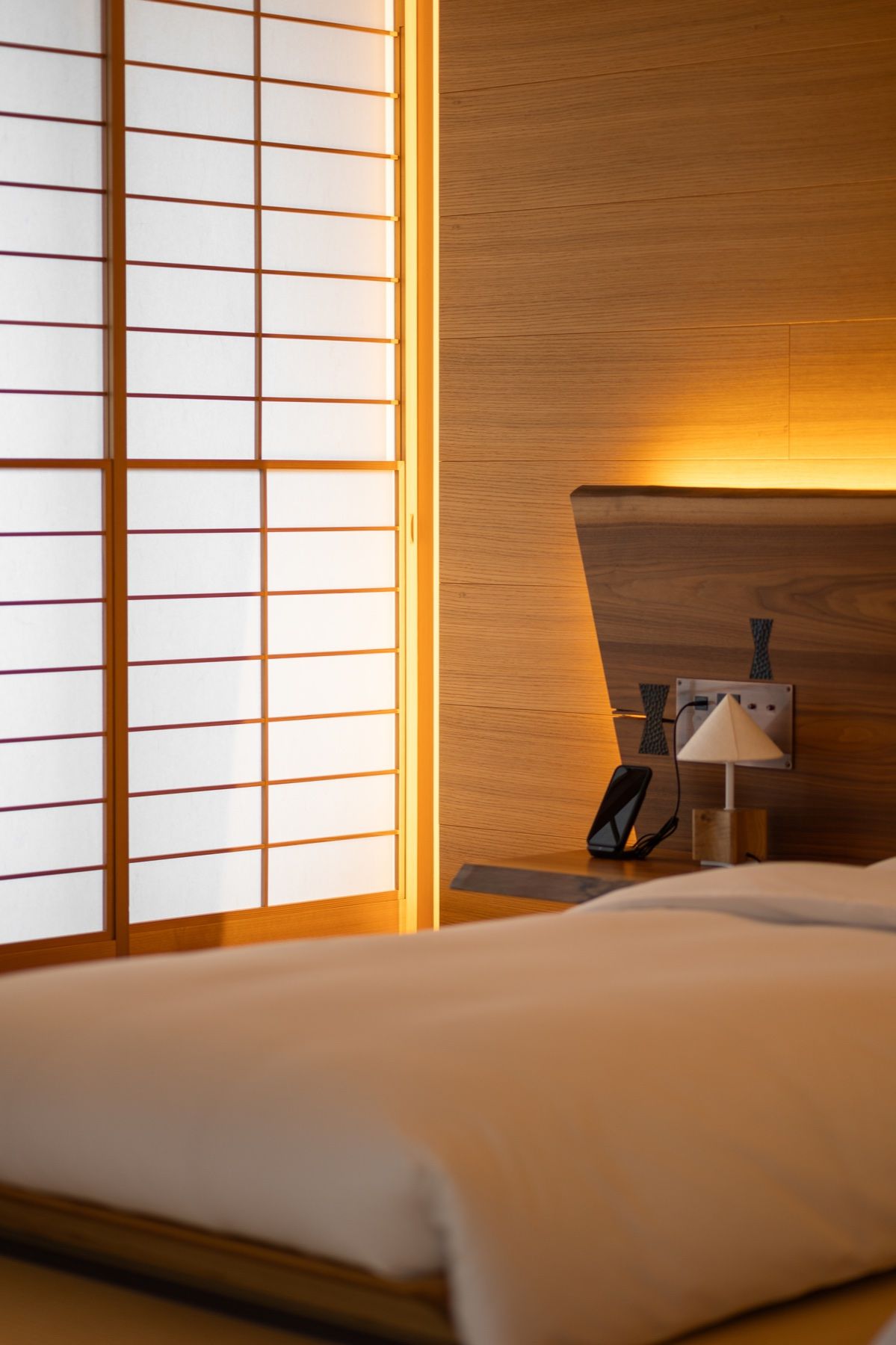 A shoji-lit hotel room, the bed made low